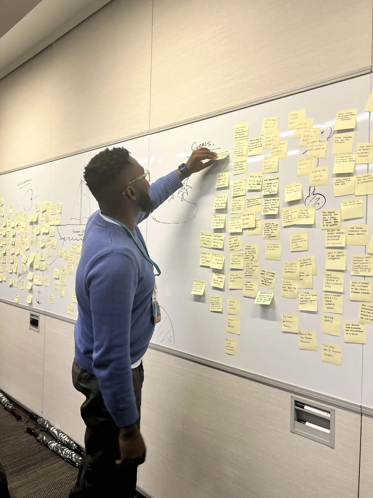 John Iseghohi, founder of Weekend MVP, adding a sticky note to a planning wall